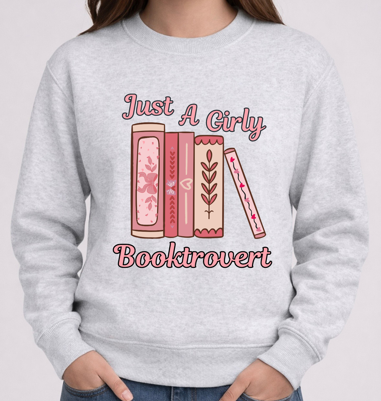 Gray sweatshirt with 'Just A Girly Booktrovert' text and book illustrations on a plain background