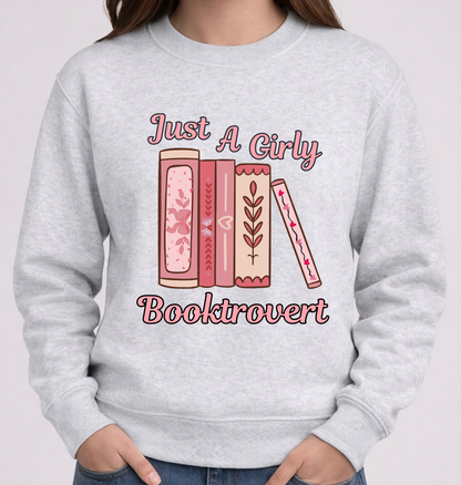 Gray sweatshirt with 'Just A Girly Booktrovert' text and book illustrations on a plain background